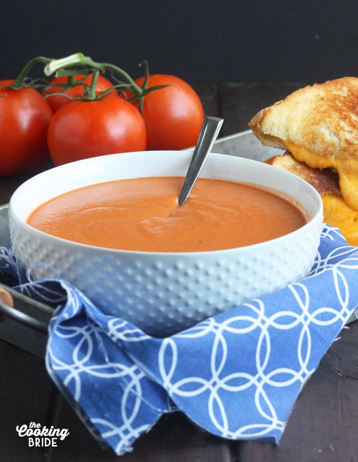 bowl of cream of tomato soup sitting on a tray with a blue napkin underneath