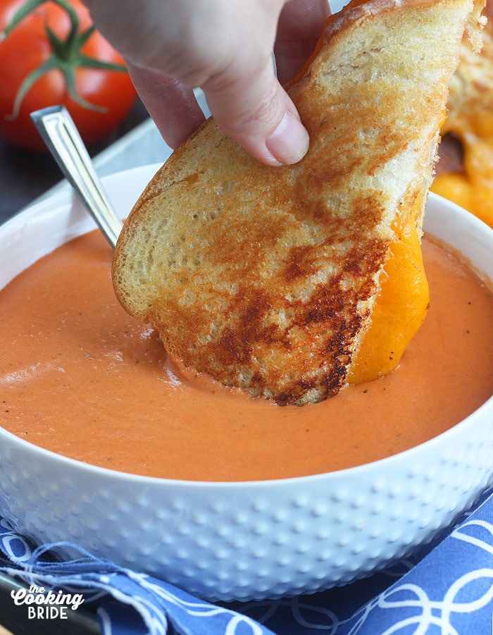 Dipping a wedge of grilled cheese sandwich into a bowl of cream of tomato soup