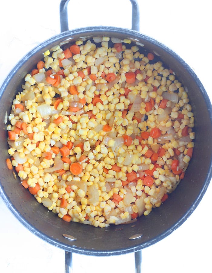 sauteeing the corn and vegetables in a large stock pot