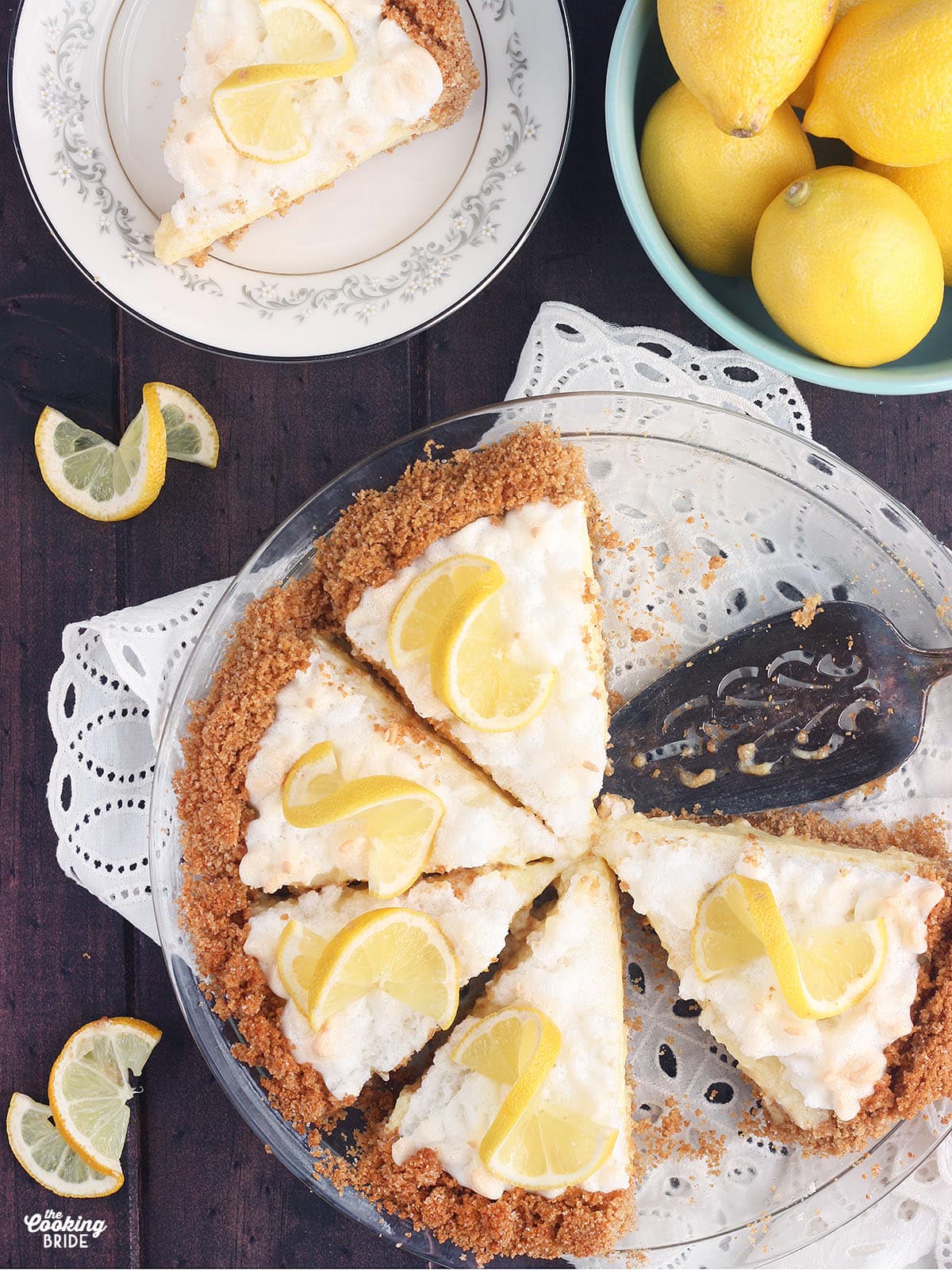 overhead shot of a lemon icebox pie in a pie plate with a slice of pie and a bowl of lemons to the side