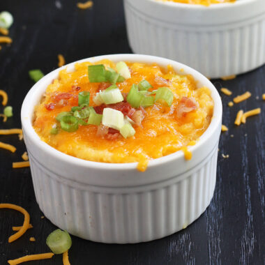 baked mashed rutabaga topped with melted cheese and green onions in a white ramekin