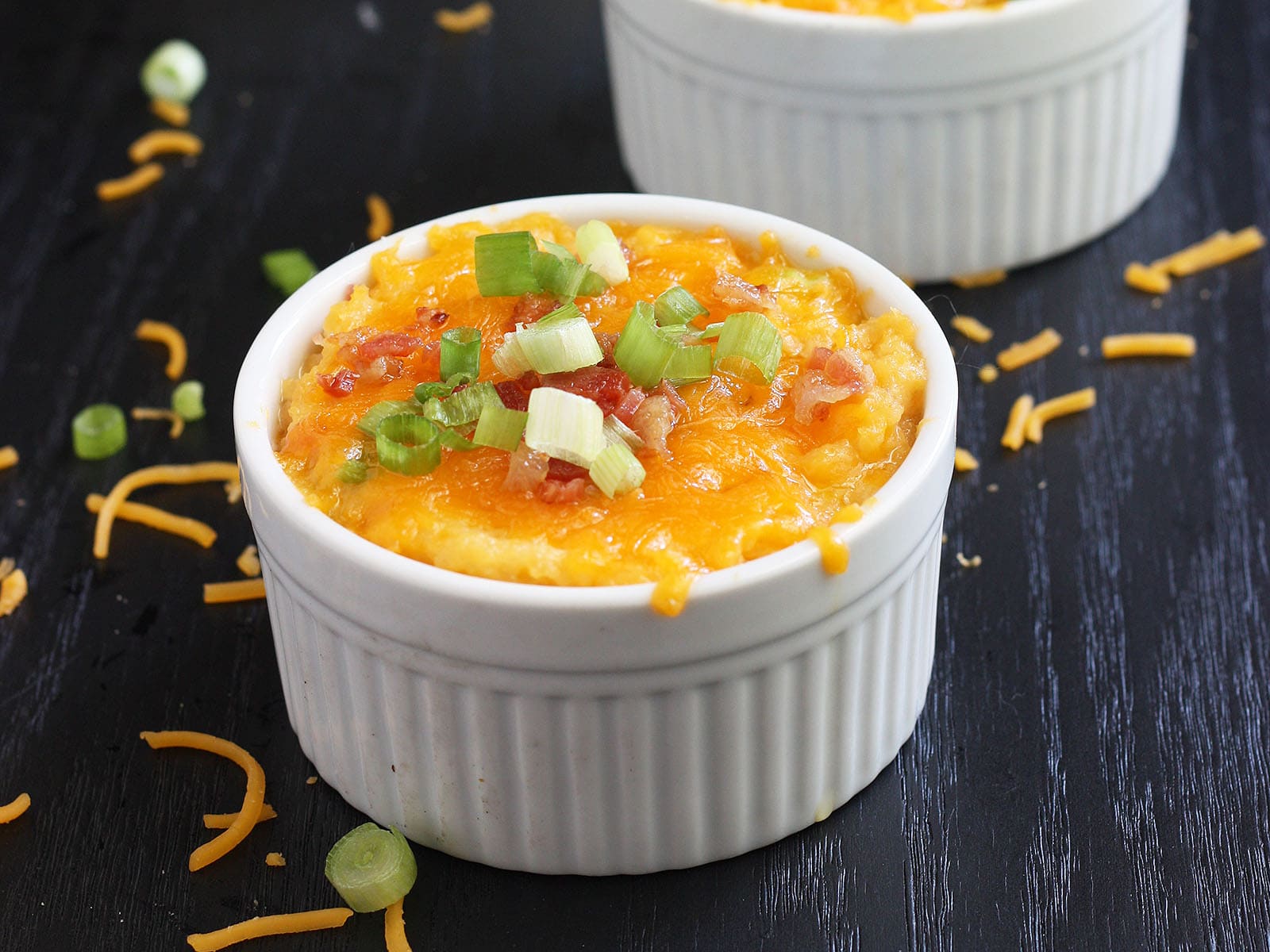 baked mashed rutabaga topped with melted cheese and green onions in a white ramekin