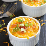 baked mashed rutabaga topped with melted cheese and green onions in a white ramekin