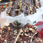 pieces of saltine toffee lined up in front of a Christmas dish full of more toffee