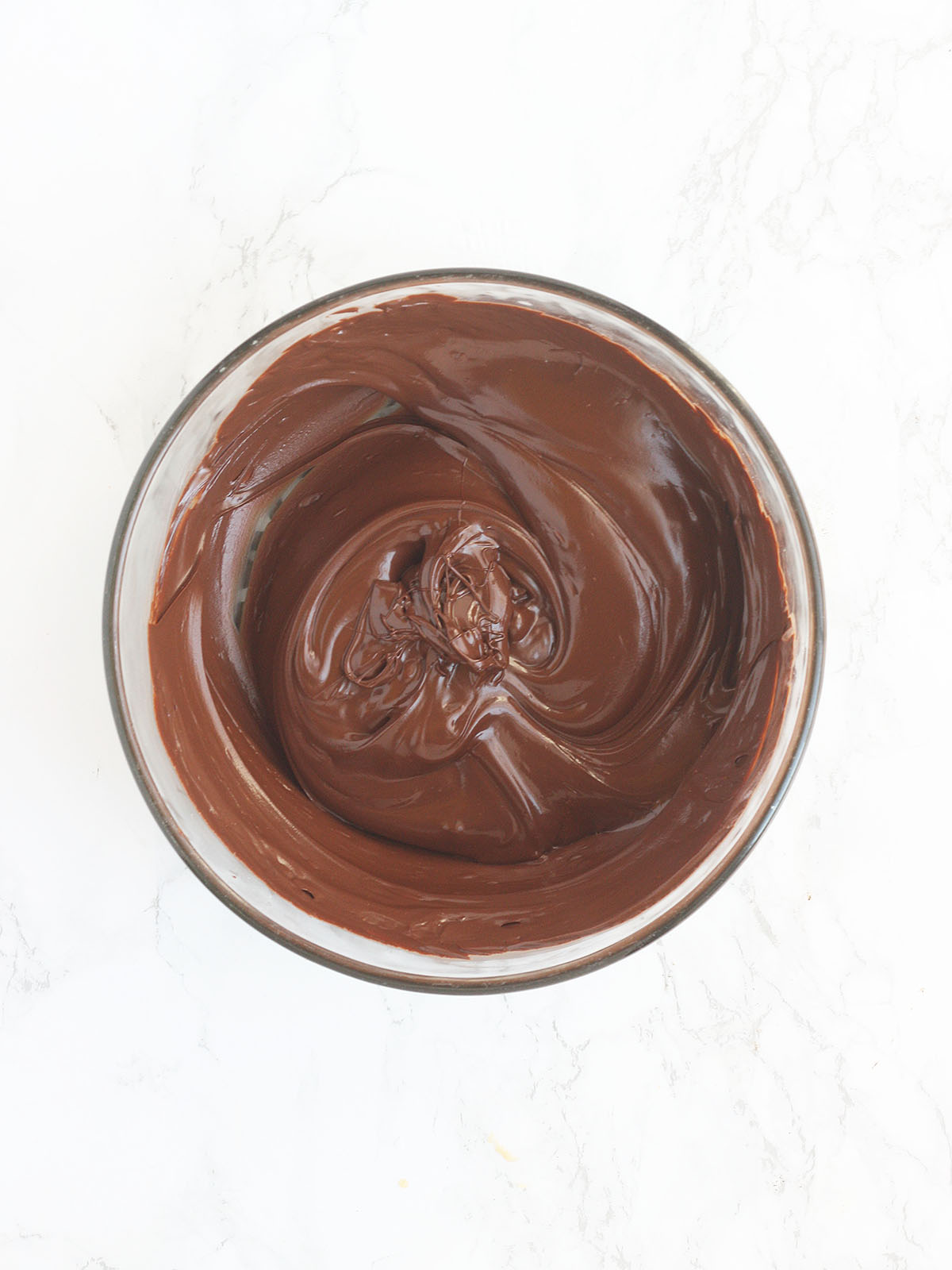 glass bowl of melted chocolate chips on a white background