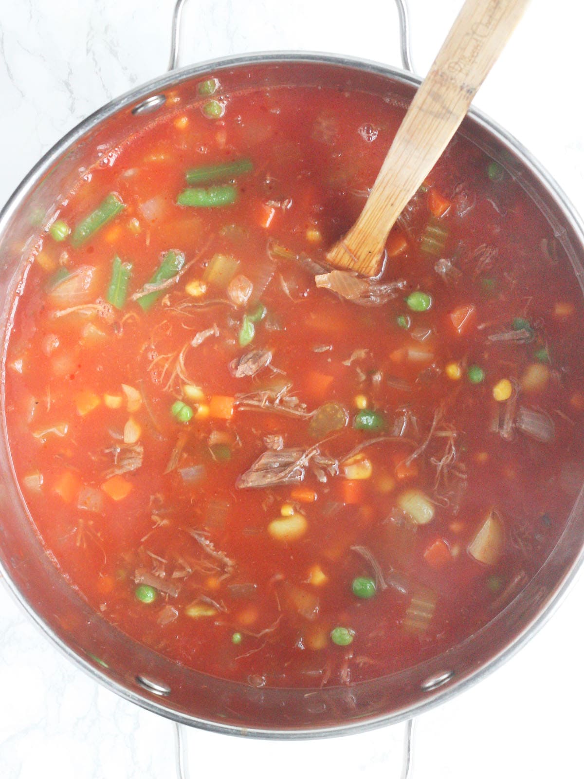 pot of vegetable beef soup with a wooden mixing spoon
