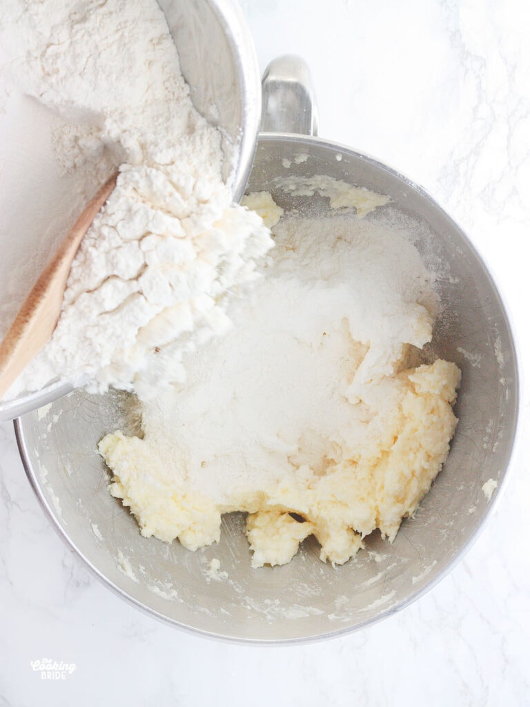 wooden spoon adding flour to creamed butter and shortening