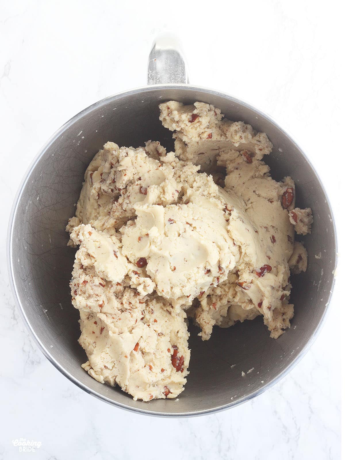 mixed cookie dough with pecans in a metal mixing bowl