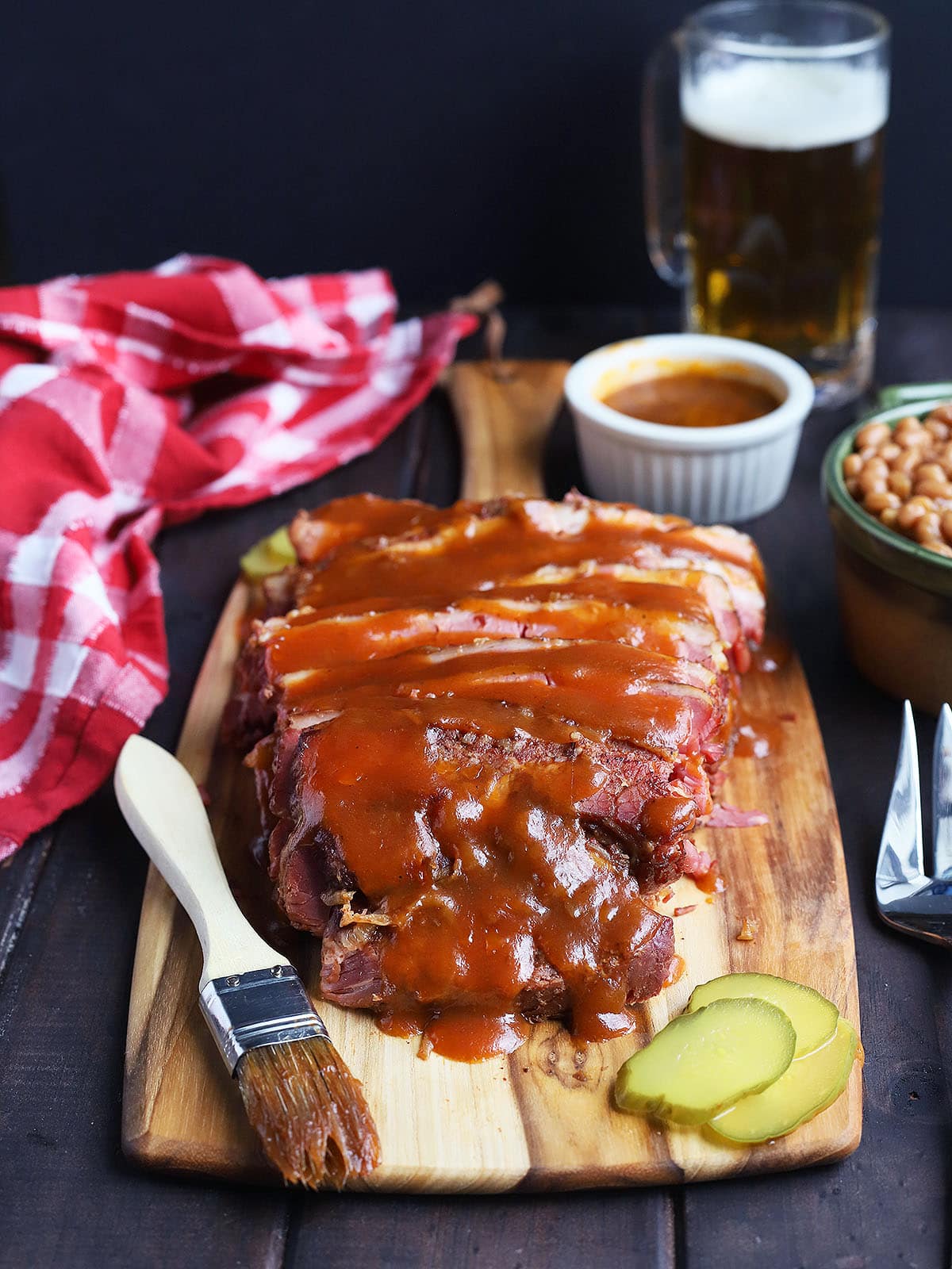 sliced brisket on a cutting board with potato salad, cole slaw and baked beans to the side