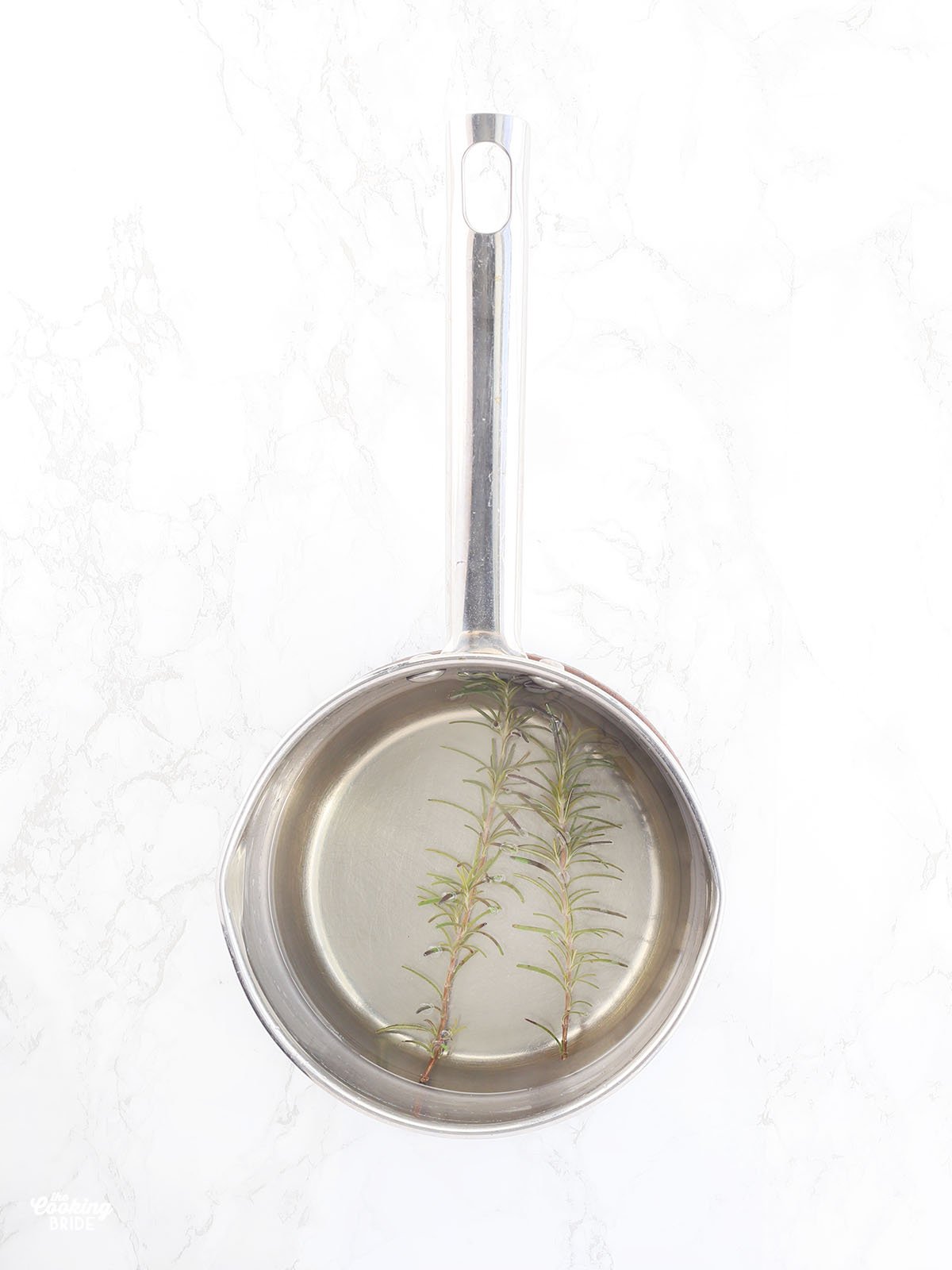 two sprigs of rosemary floating in a pan of simple syrup