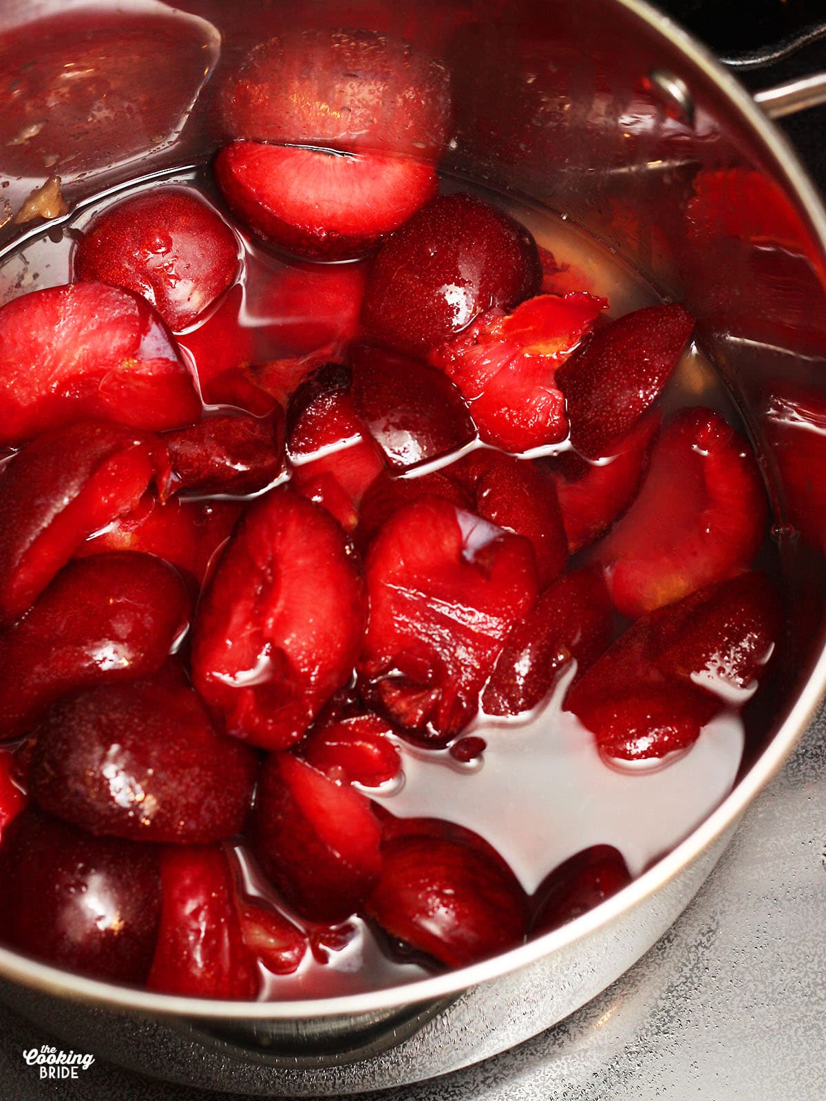 sliced plums in a metal stock pot covered with water