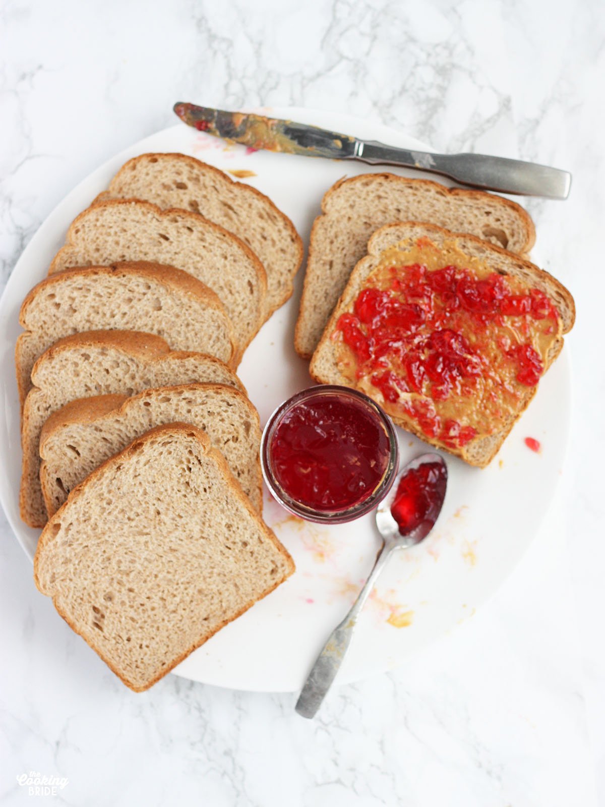 plate of sliced bread with peanut butter and plum jelly