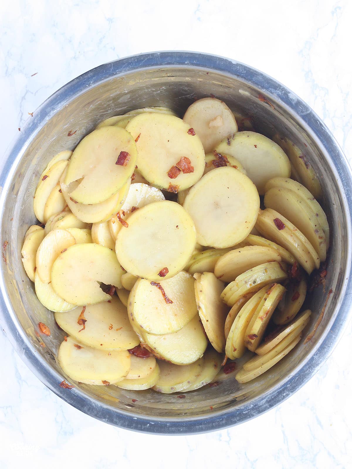 thinkly sliced Yukon gold potatoes in a metal mixing bowl