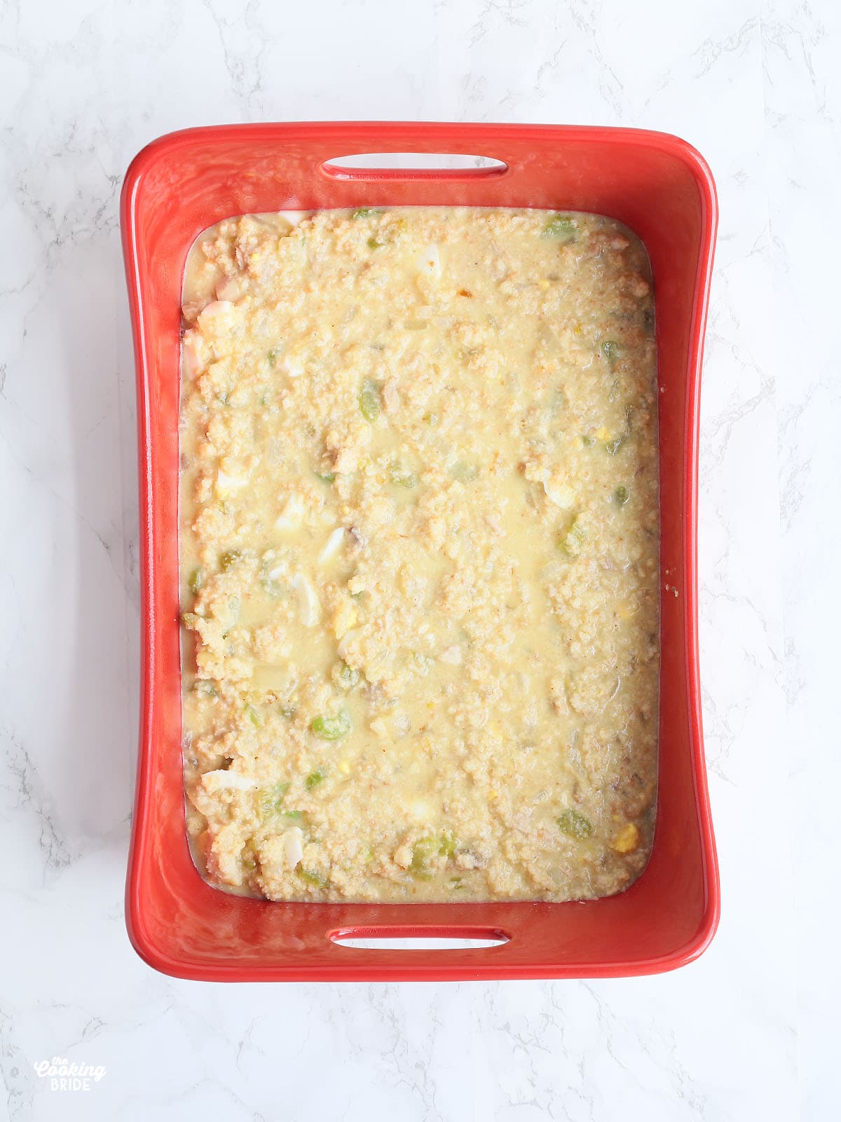 unbaked cornbread dressing in a red baking dish