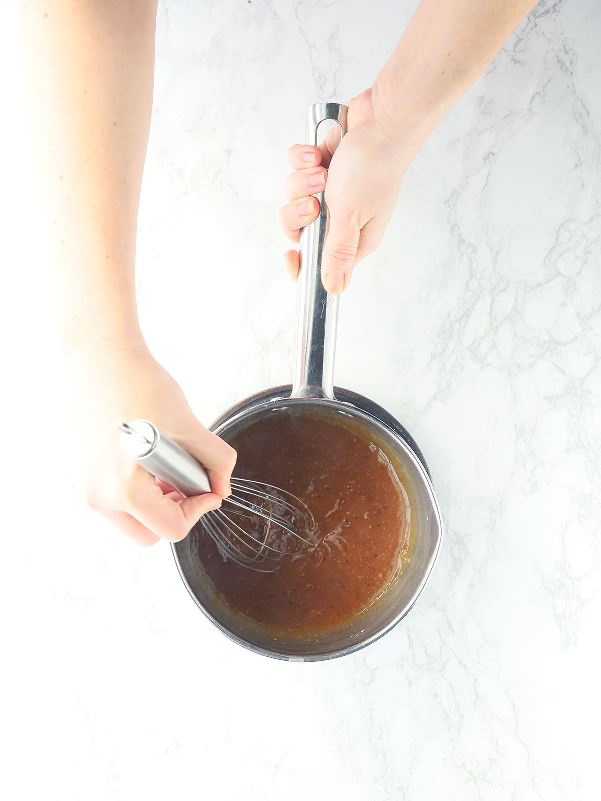 hand whisking glaze ingredients together in a small saucepan