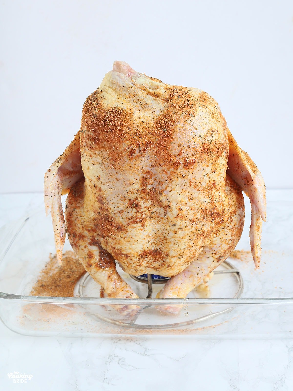 uncooked drunk chicken on a roaster sitting in a glass casserole dish