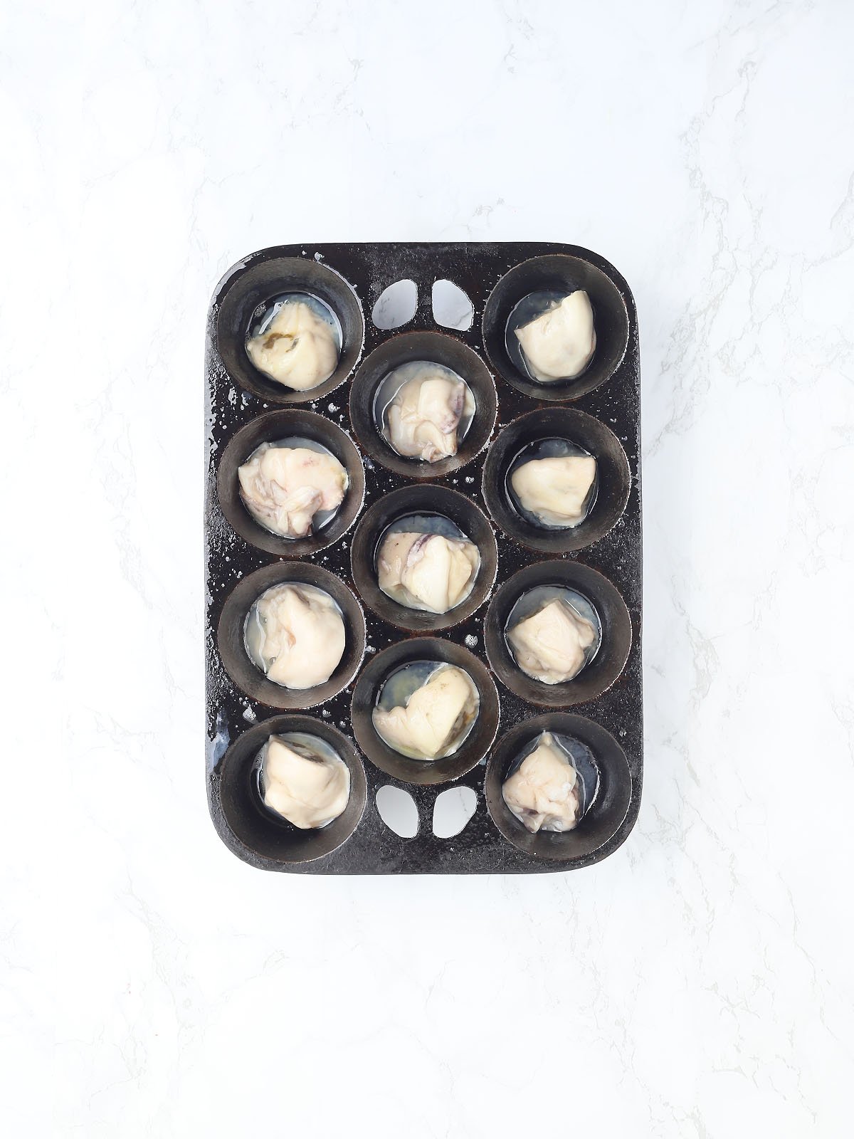 raw oysters in a muffin pan
