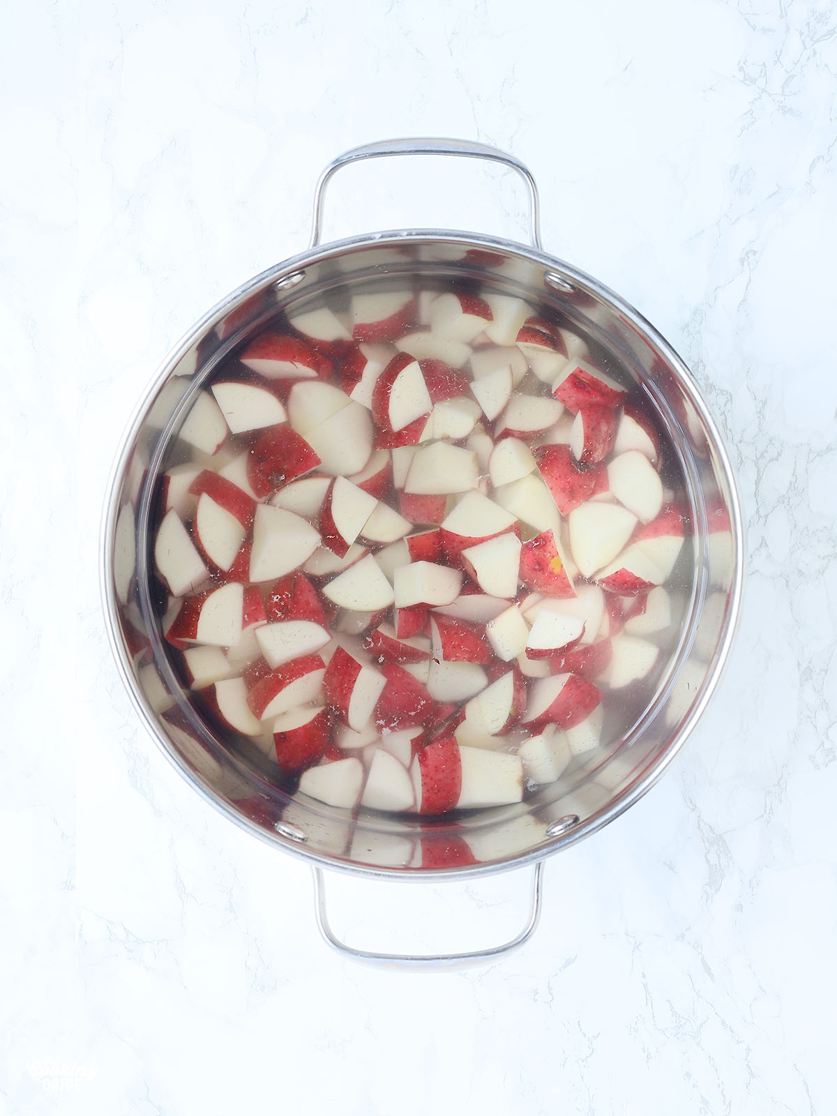 quartered red potatoes in a stainless steel stockpot covered with water