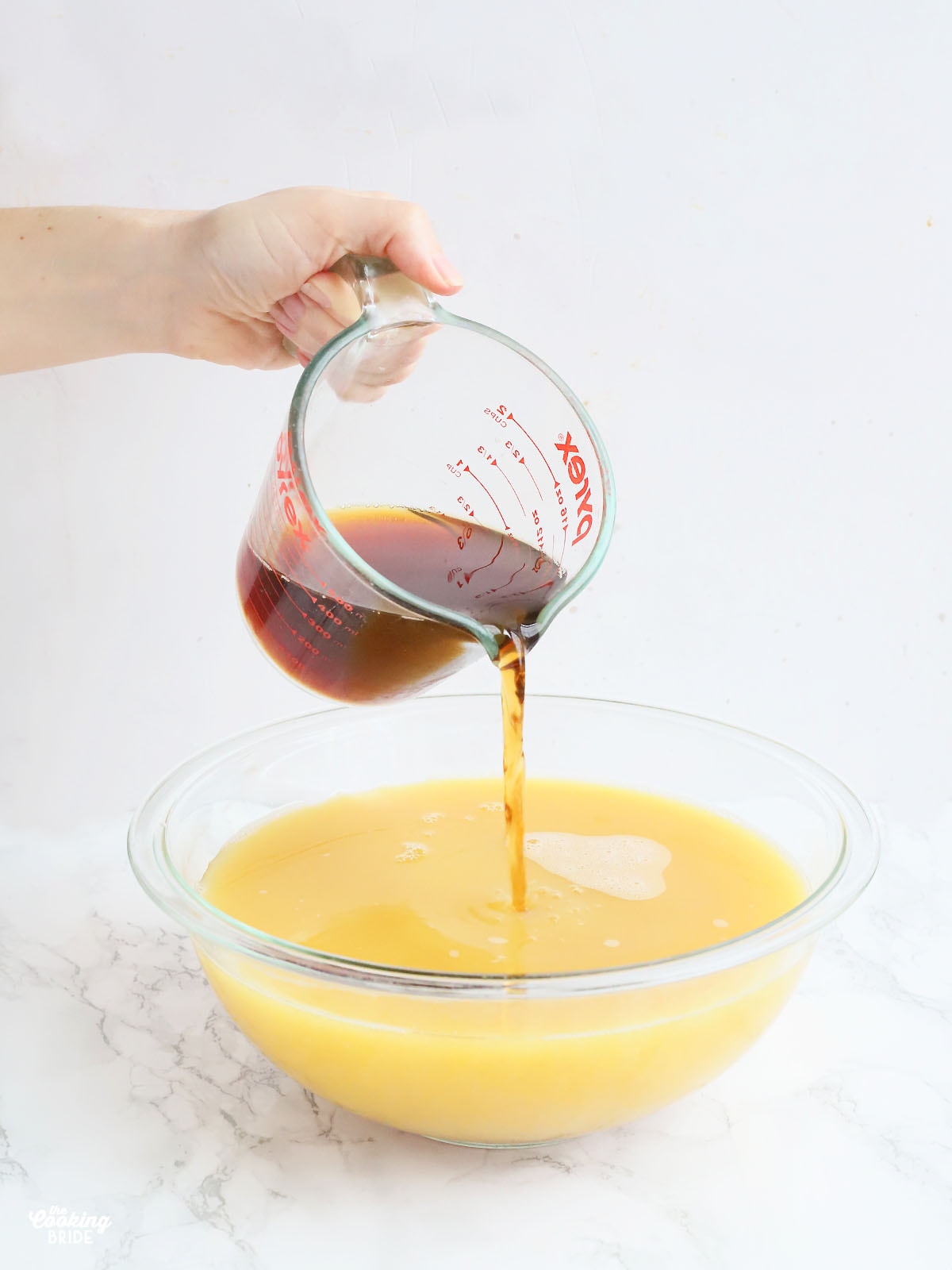 hand pouring sweet tea into a large mixing bowl filled with juice