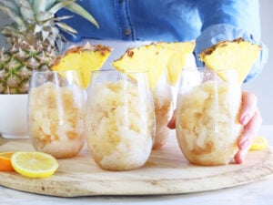 woman setting a glass of bourbon slush on a round wooden tray