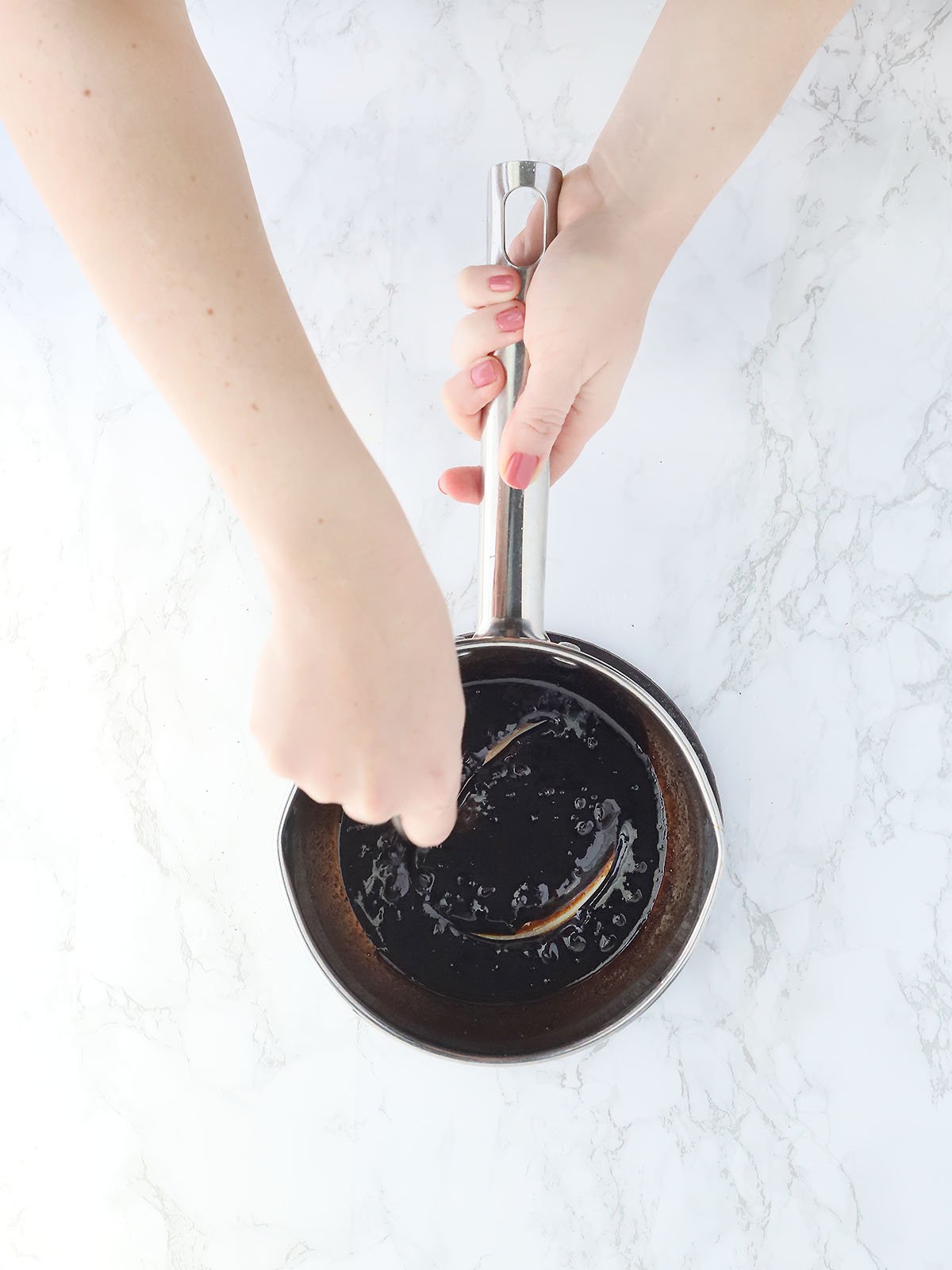hand stirring molasses glaze in a small saucepan