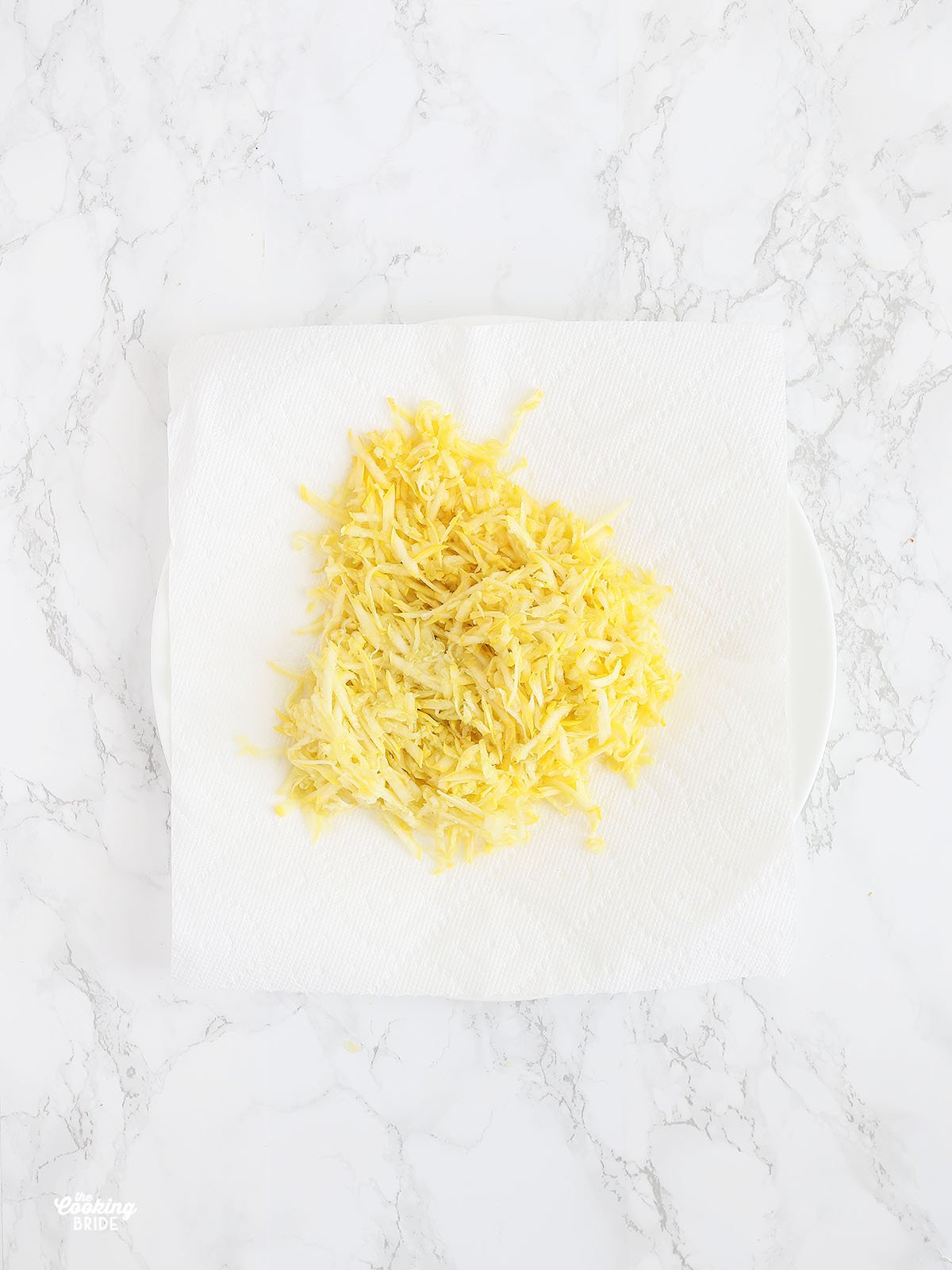 shredded yellow squash drying on a layer of paper towels.