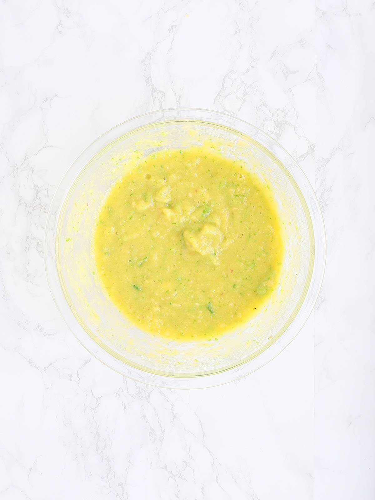 Pureed peaches and jalapeno peppers in a large glass mixing bowl.