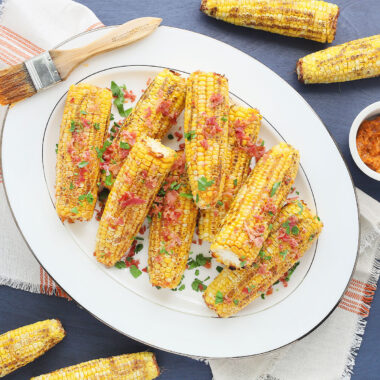 overhead shot of roasted corn with bacon butter on a large white platter