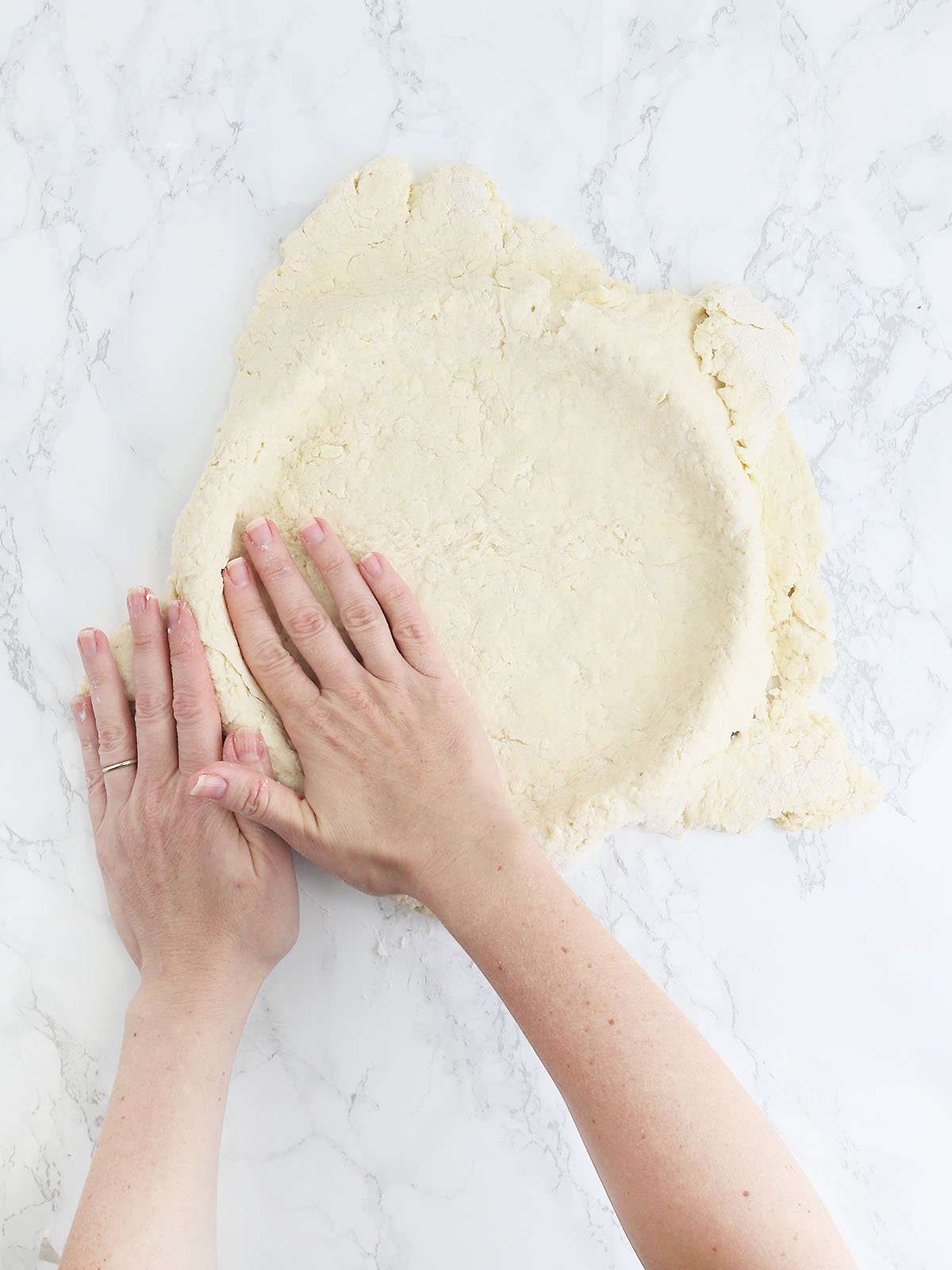 hands pressing biscuit crust into a tart pan
