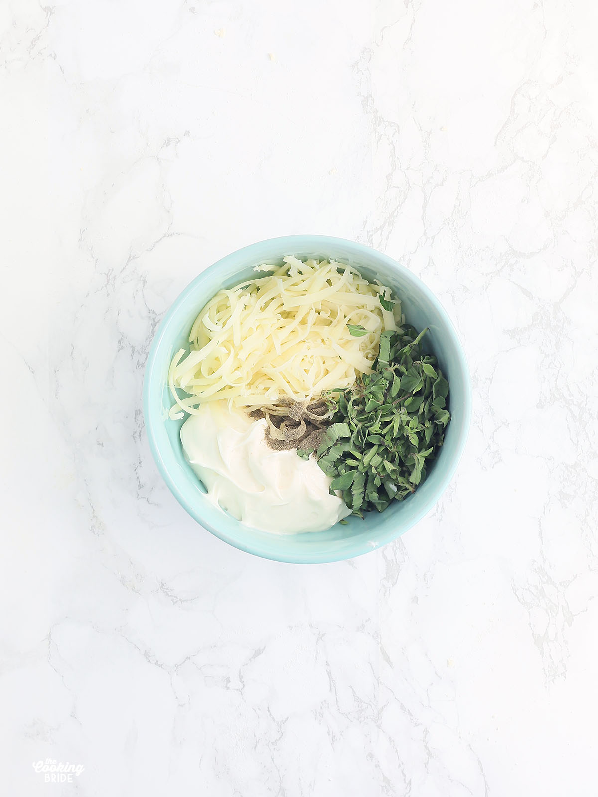 cheese, mayo and fresh herbs in a blue bowl