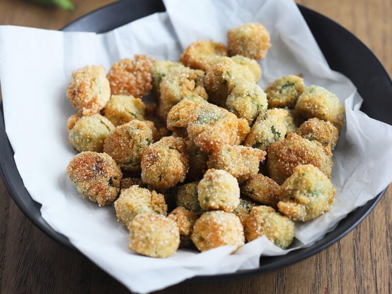 Black dish of fried okra on a wooden background.