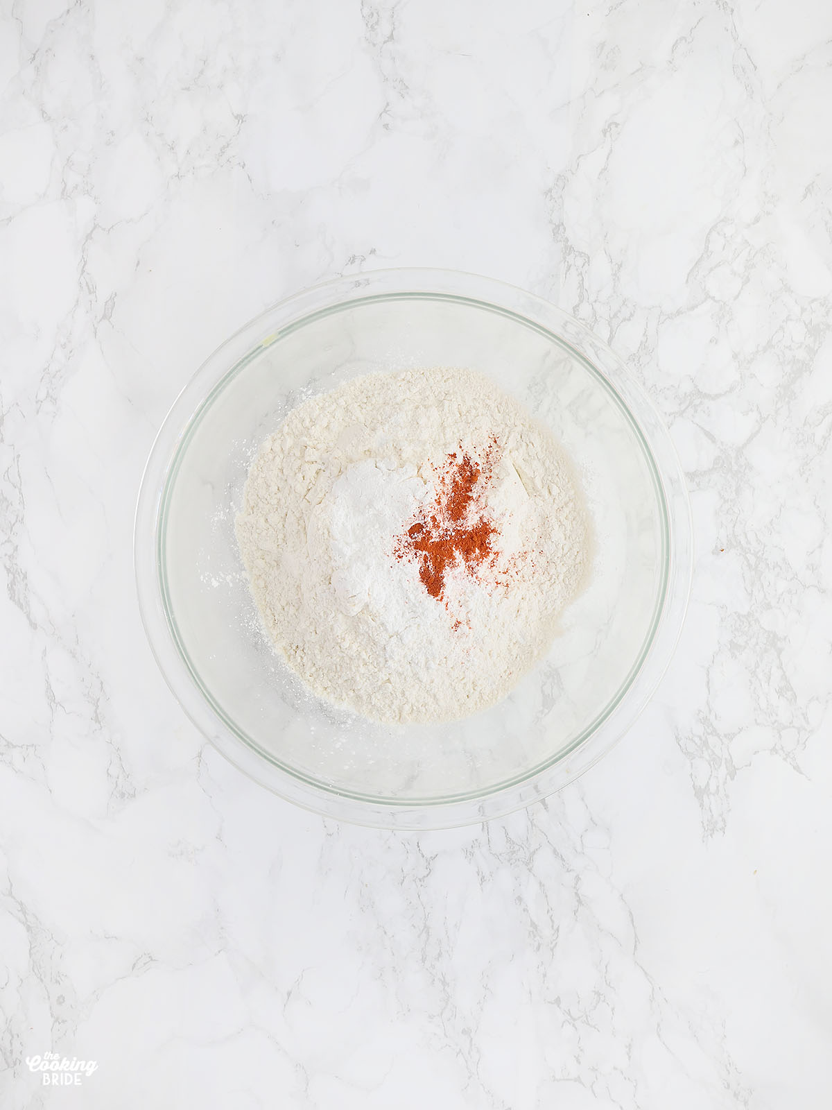 glass mixing bowl with white cornmeal, all-purpose flour, baking powder, and cayenne pepper