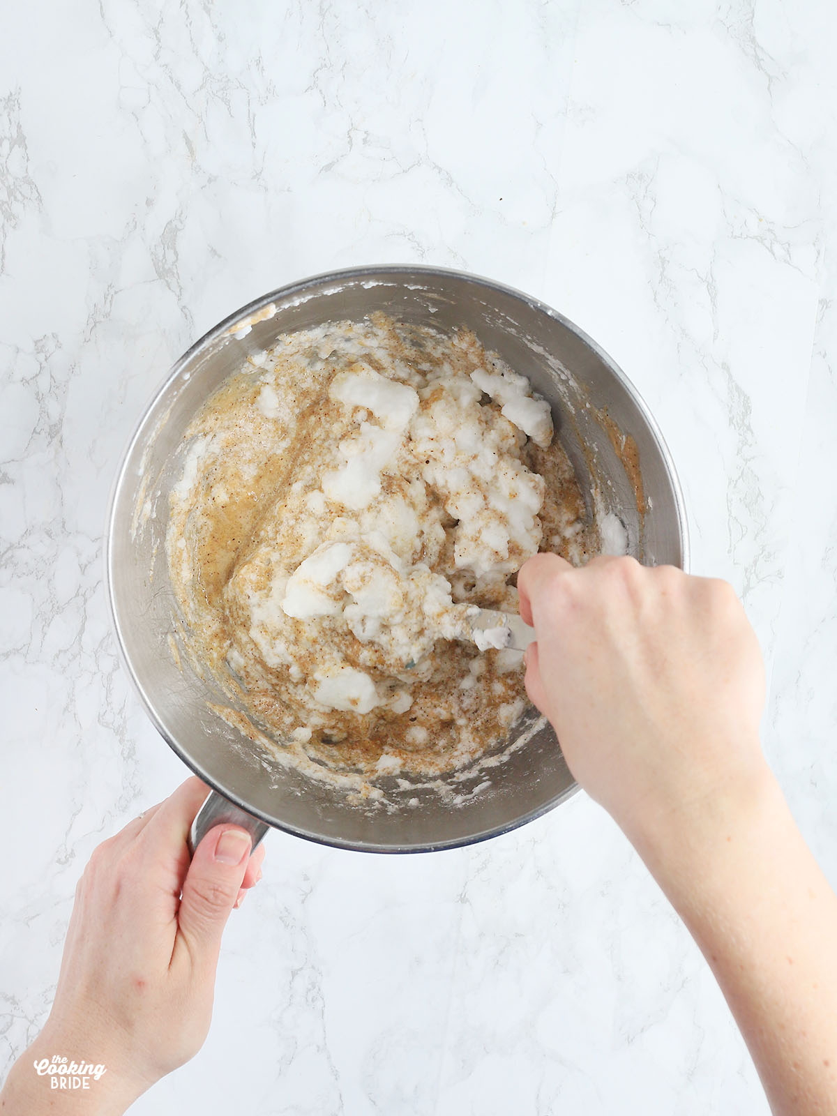 hands gently folding the egg whites into the cake batter with a spatula