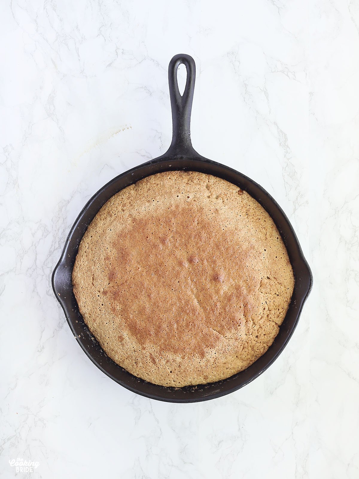 baked cake in a cast iron skillet before being inverted on a plate