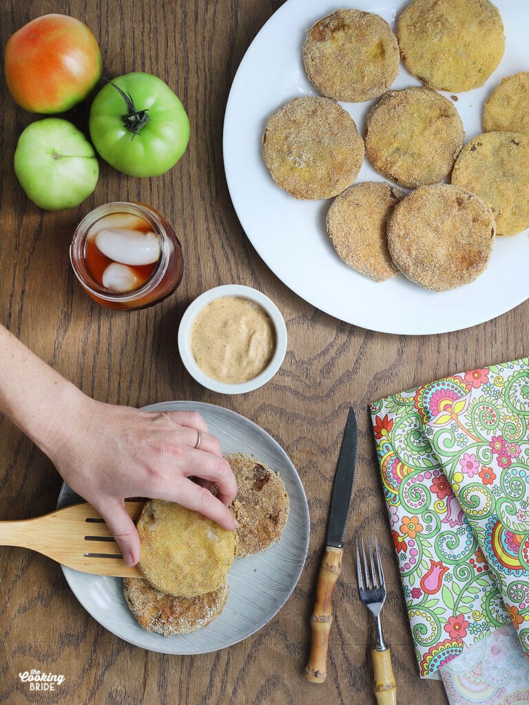 hand placing fried green tomatoes on a plate