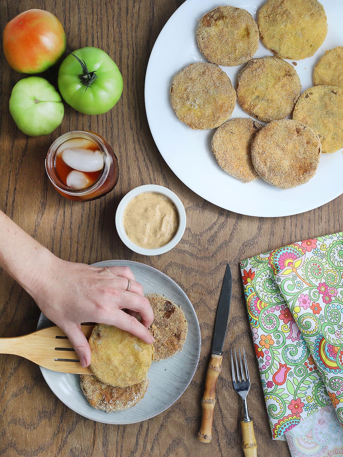 Hand placing fried green tomatoes on a plate.