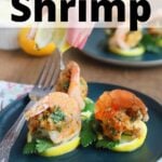 three crab stuffed shrimp with a fork on a teal plate