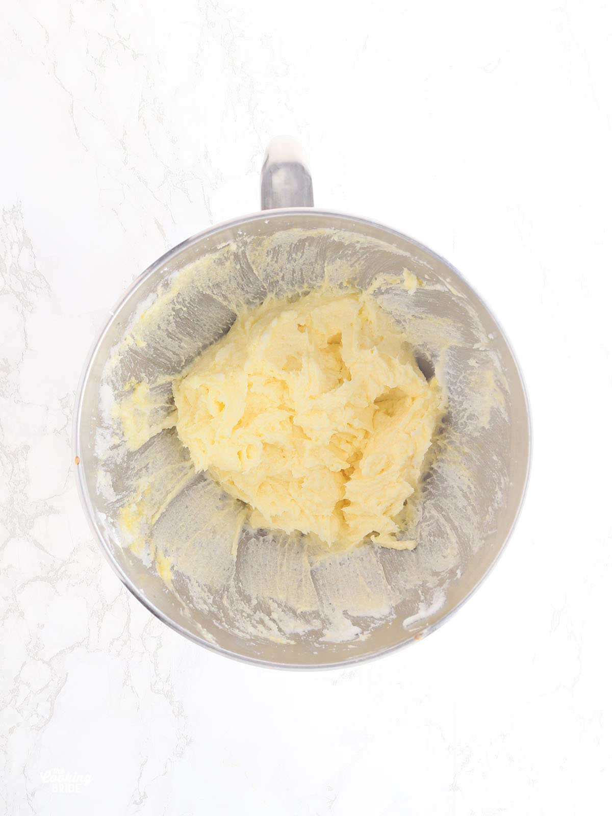 overhead shot of creamed shortening, eggs and sugar in a metal mixing bowl