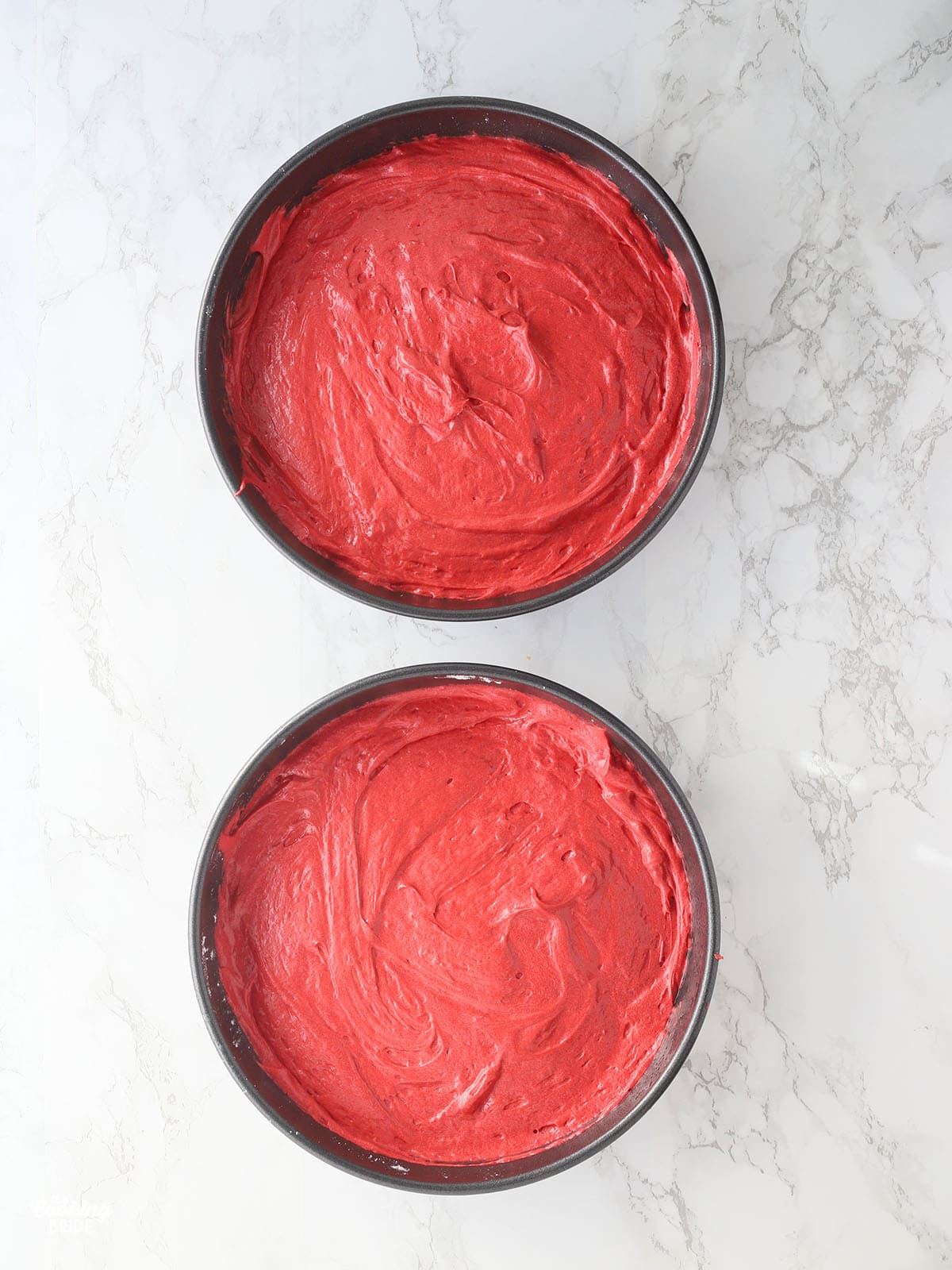 overhead shot of red velvet cake batter divided into two 8-inch round cake pans
