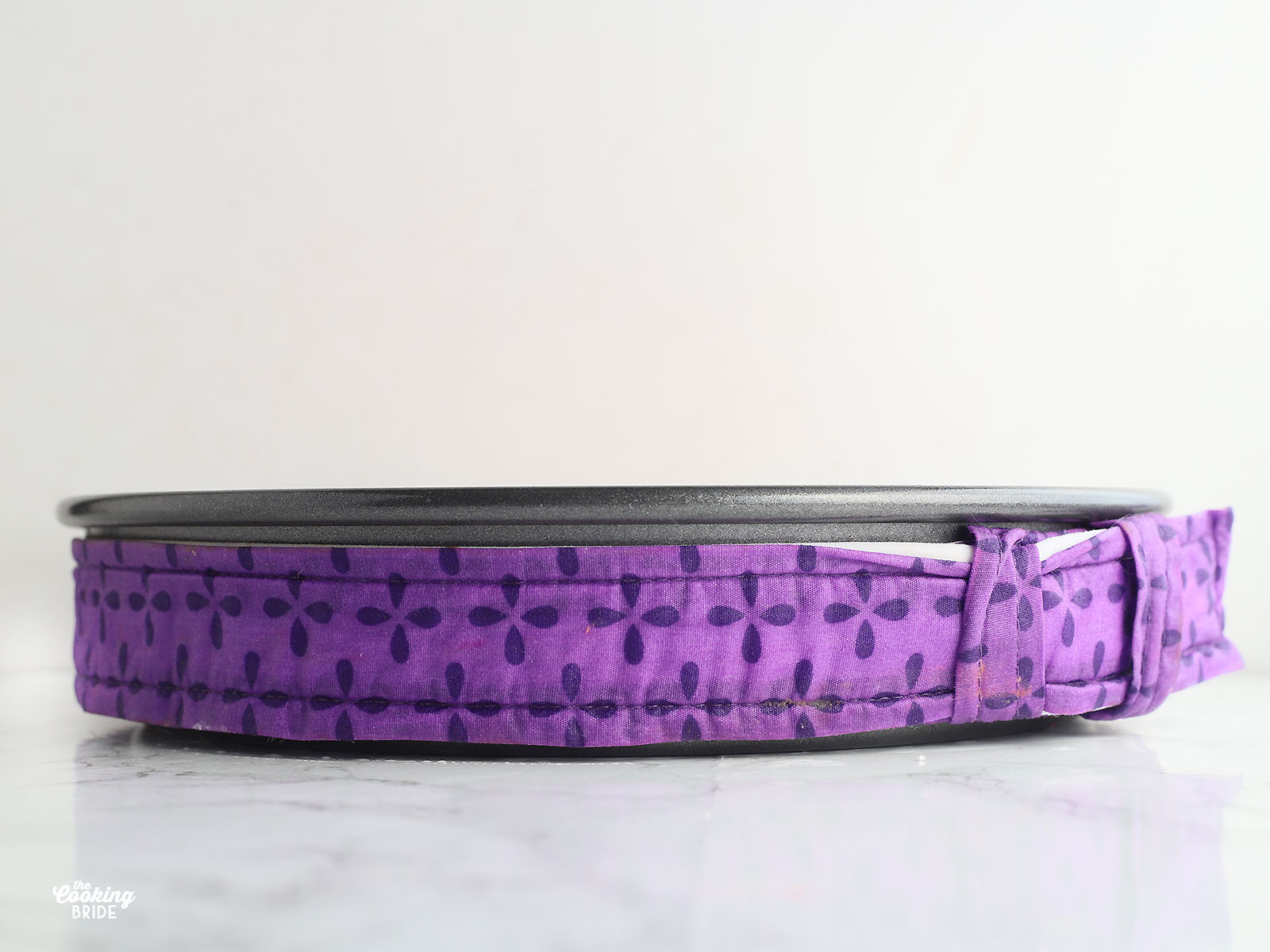 cake pan wrapped in a purple cloth cake strip