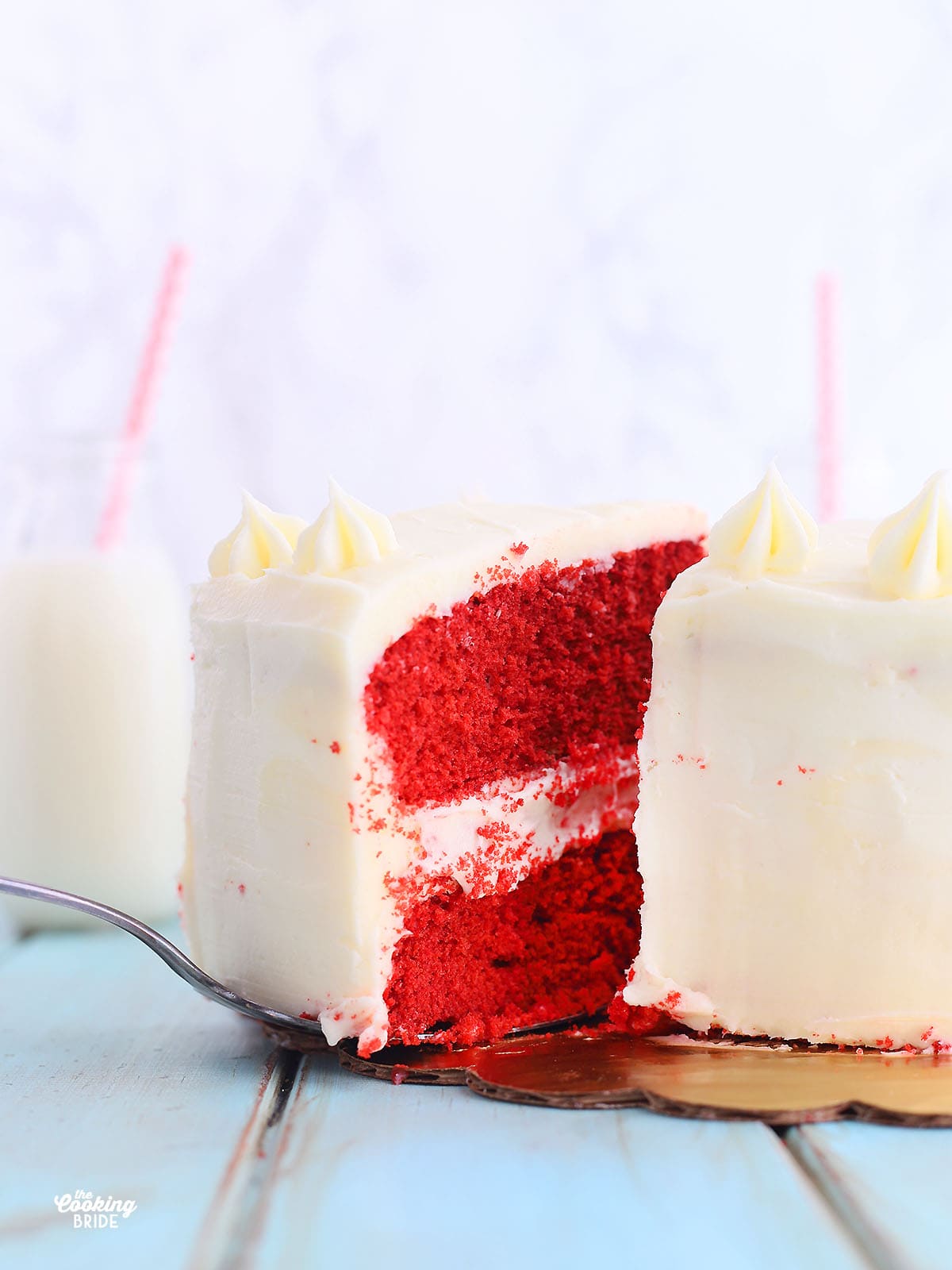 slice of red velvet cake being lifted from the rest of a cake with a cake spatula