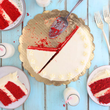 overhead shot of sliced red velvet cake with three slices of cake on plates and bottles of milk to the side
