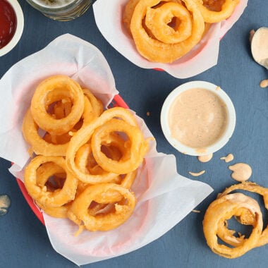 overhead shot of beer battered onion rings in two paper lined red baskets