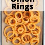 Overhead shot of beer battered onion rings draining on a cookie sheet lined with brown paper bags