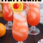 side shot of a hurricane cocktail garnished with a cherry and orange slice, three other glasses in the background