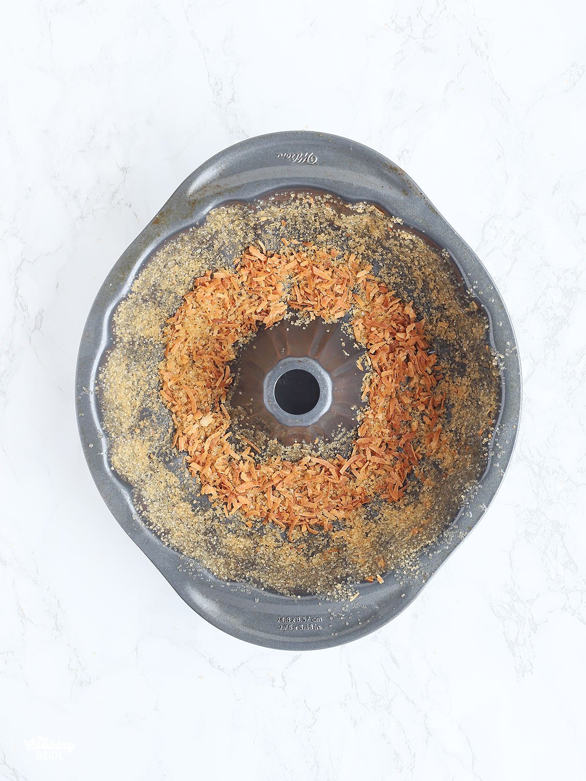 greased Bundt cake pan sprinkled with raw sugar and toasted coconut