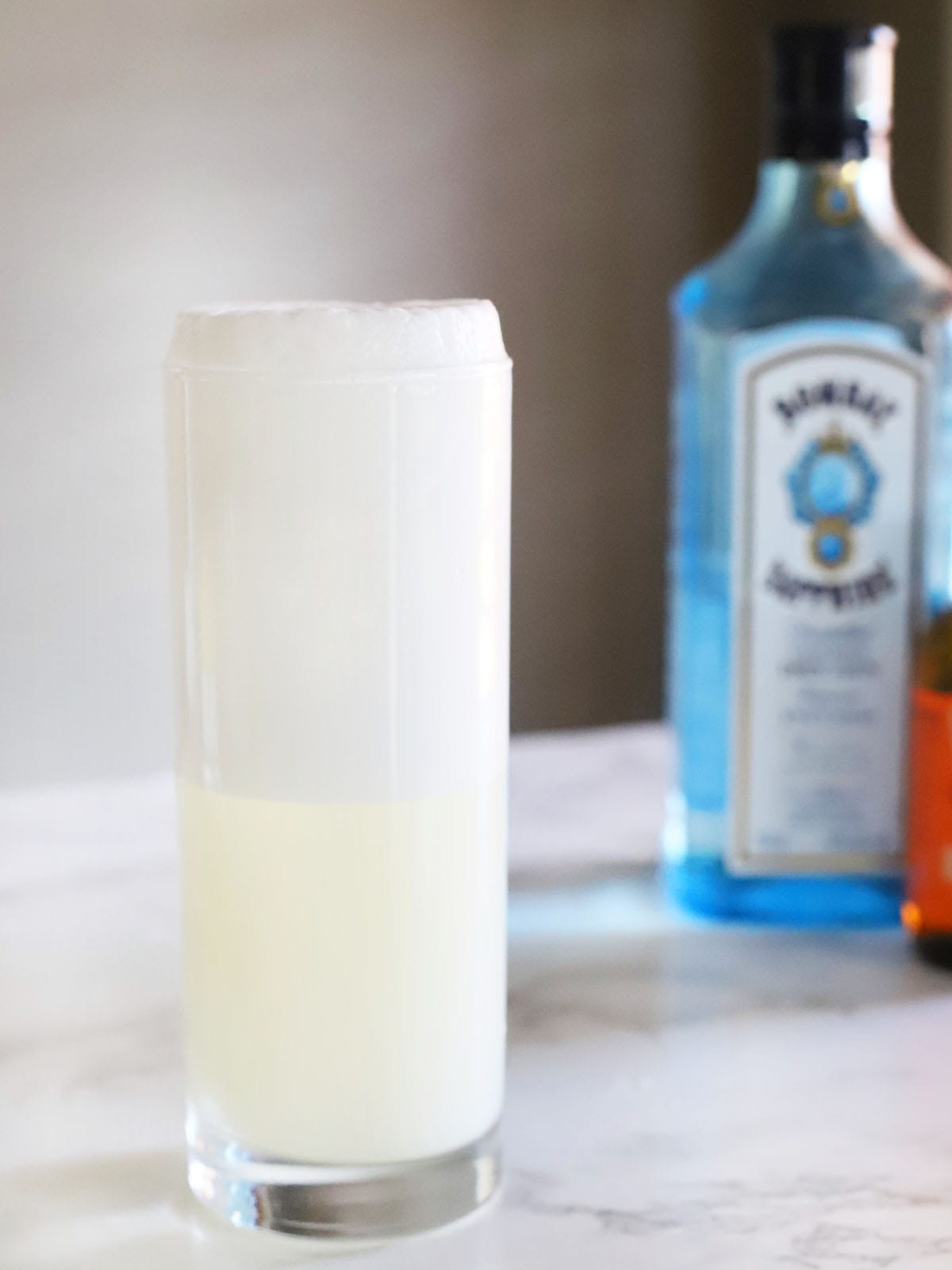 side view of the foam of a Ramos gin fizz rising above the rim of the glass