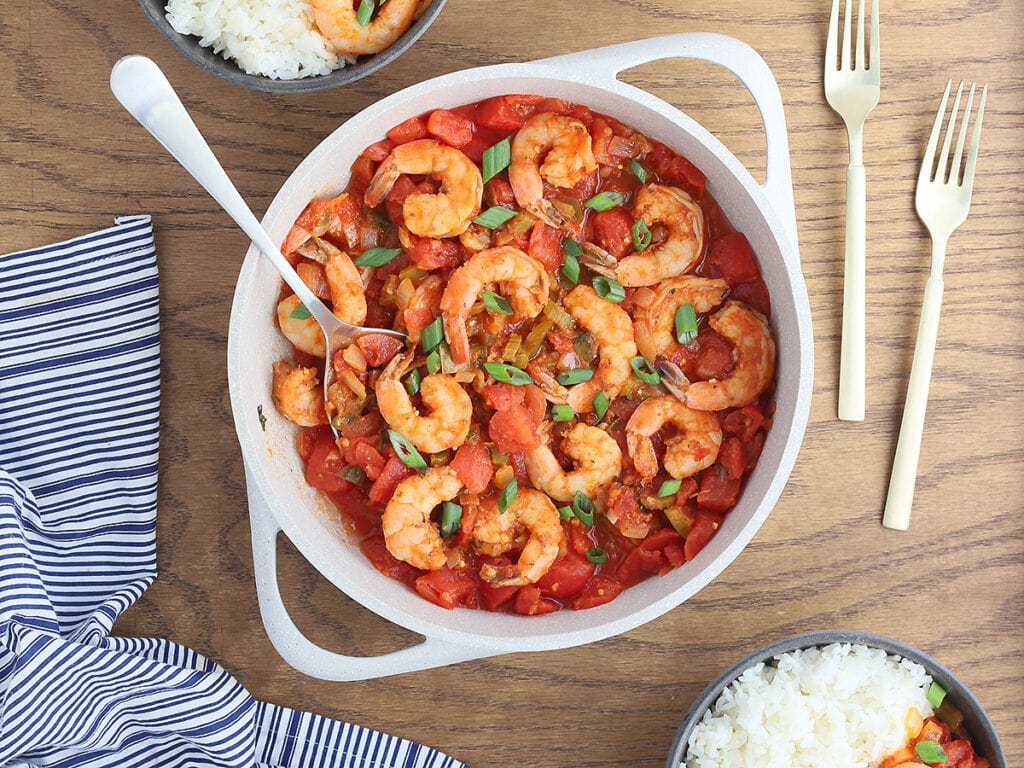 large white casserole dish of shrimp creole garnished with sliced green onions