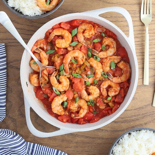 large white casserole dish of shrimp creole garnished with sliced green onions