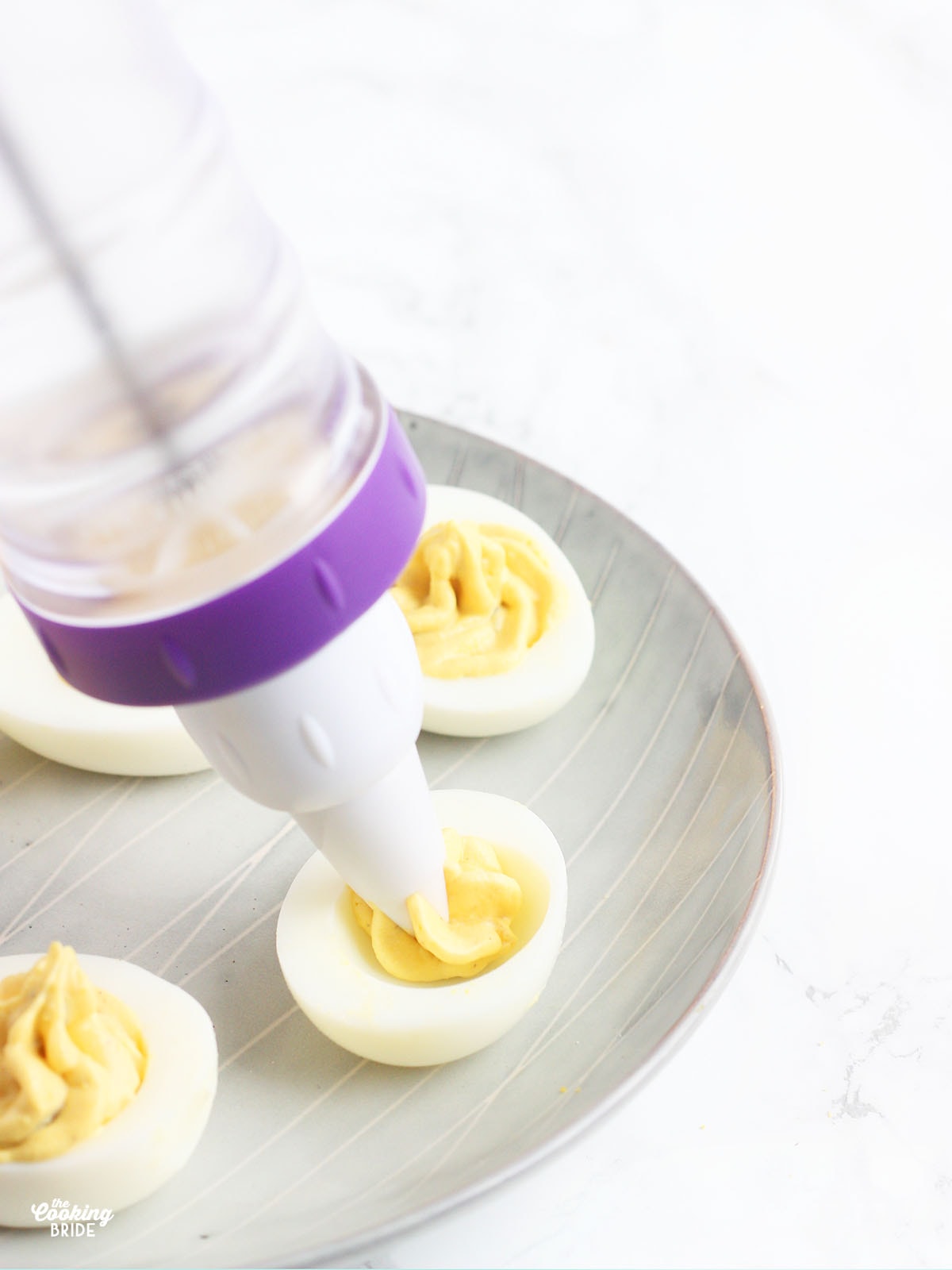 piping deviled egg filling into hollowed out egg yolks